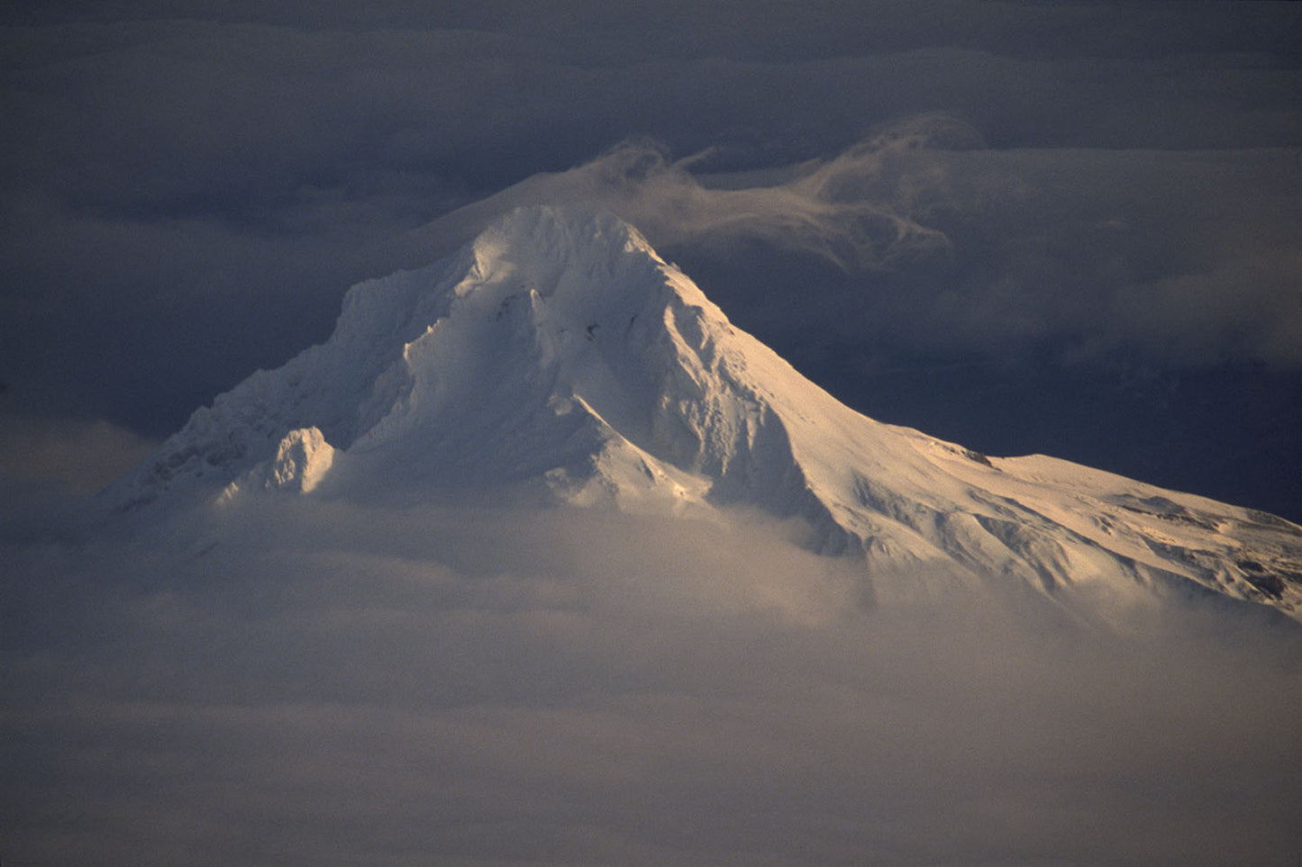 Wispy clouds and fog cover the summit of a snow covered Mt. Hood in Oregon.