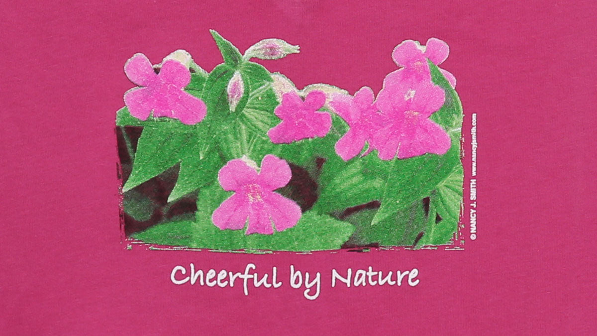 Detail view of shirt screen print on color fuschia, featuring pink blooming Monkey Flowers with caption "Cheerful by Nature".