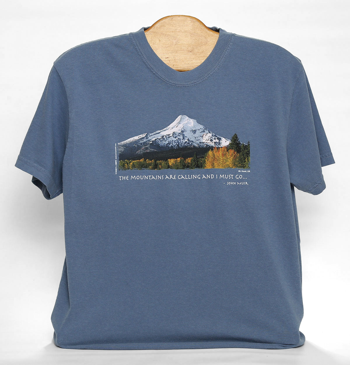 Front view of Mt Hood/Men's T-shirt, colored blue jean. Features print of Oregon's Mt. Hood and fall trees. Caption reads "The Mountains are Calling and I Must Go...".