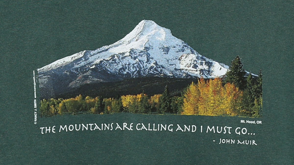 Detail view of shirt print on blue spruce green. Features Oregon's Mt Hood and fall trees with caption "The Mountains are Calling and I Must Go..."