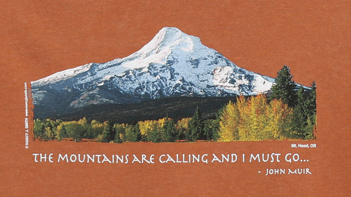 Detail view of shirt screen print on color yam orange. Shows Oregon's Mt Hood and fall trees with caption "The Mountains are Calling and I Must Go..."