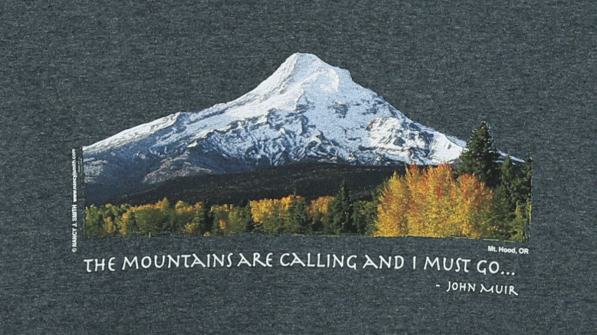 Detail view of shirt print on color dark grey heather. Features Oregon's Mt Hood and fall trees with caption "The Mountains are Calling and I Must Go..."