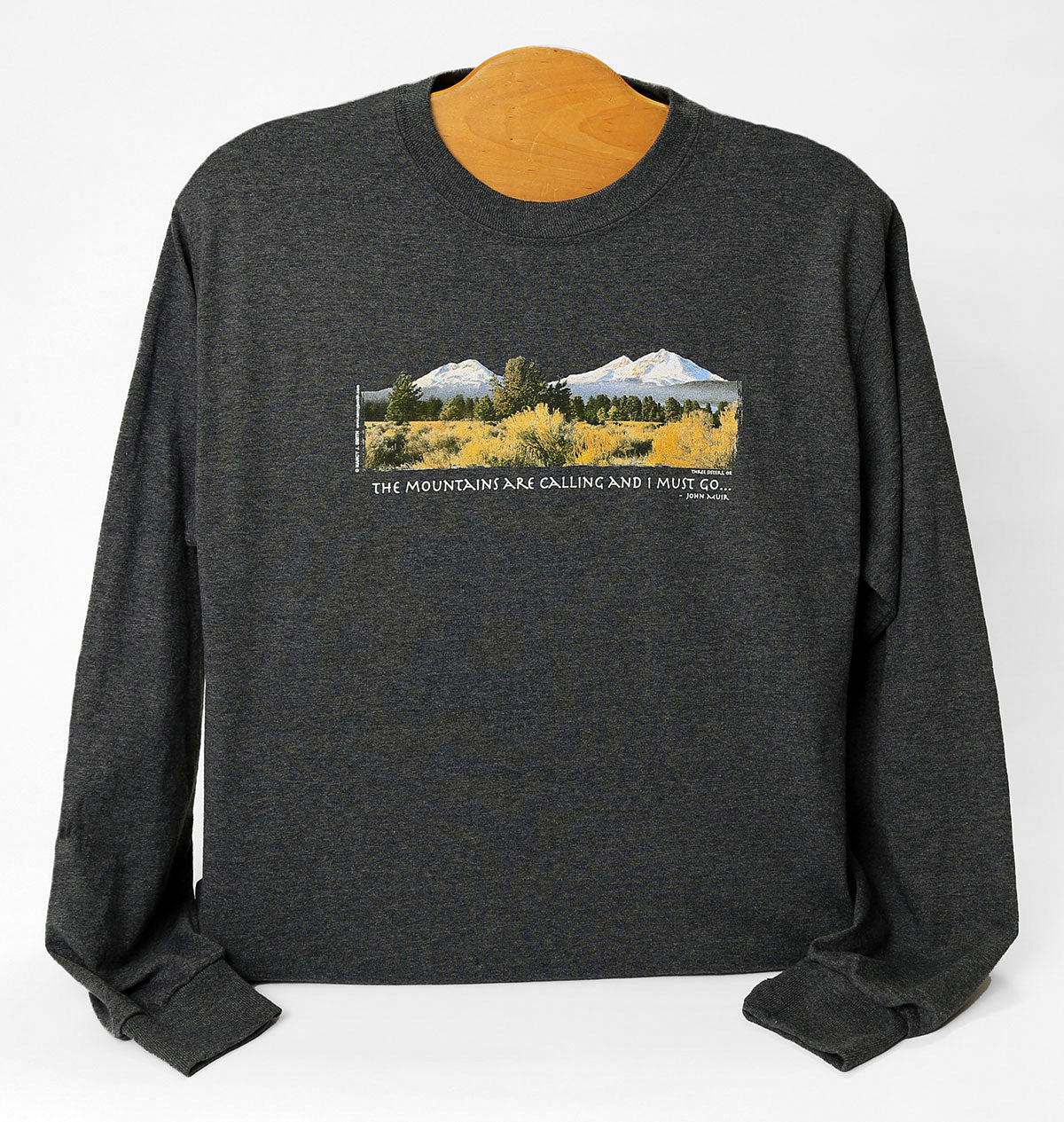 Front view of Three Sisters/Mountains are Calling long sleeve shirt in dark heather grey. Features print of Oregon's Three Sisters mountains with caption "The Mountains are Calling and I Must Go...".